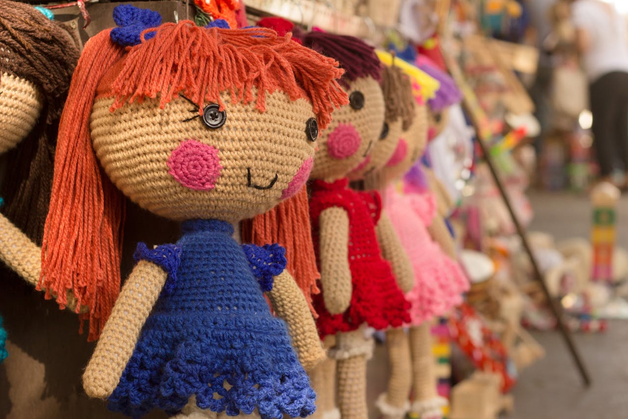 services-02 Charming crocheted dolls in bright clothes hang at a market stall.